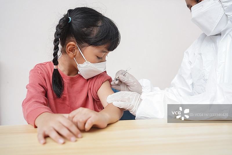 戴口罩的小病人在医院接受护士的冠状病毒或流感疫苗注射。疫苗、免疫、疾病预防的概念。图片素材