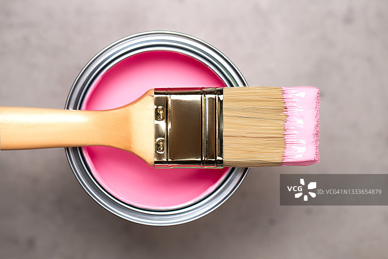 用粉色颜料在金属桶上刷漆，用于混凝土灰色背景上的翻新工程。家居室内装修理念。平铺风格和特写图片素材