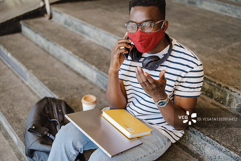 非裔美国大学生戴着防护口罩在打电话图片素材