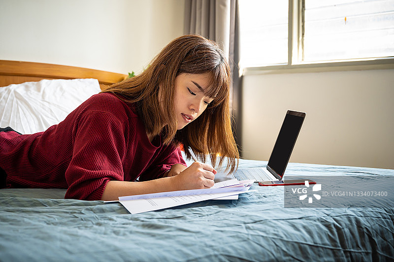 年轻的亚洲女企业家在床上使用笔记本电脑图片素材