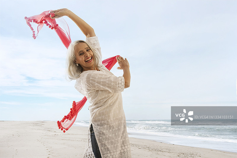 一个老妇人在沙滩上玩她的春泥。图片素材
