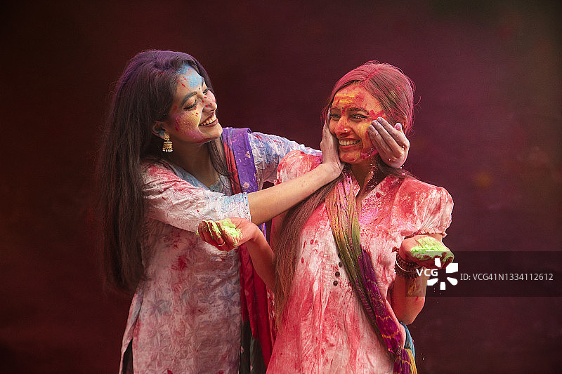 胡里节期间，一名年轻女子高兴地为她的朋友涂上颜色图片素材