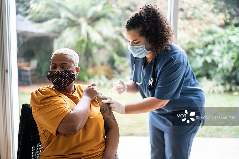 护士佩戴防护口罩为妇女接种疫苗图片素材