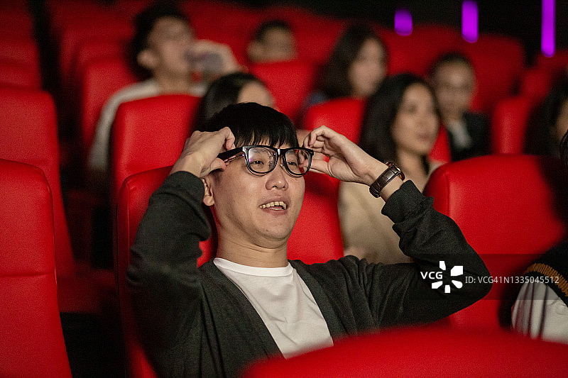 近距离观察亚洲华人观众使用3D眼镜在电影院观看3D电影的兴奋图片素材
