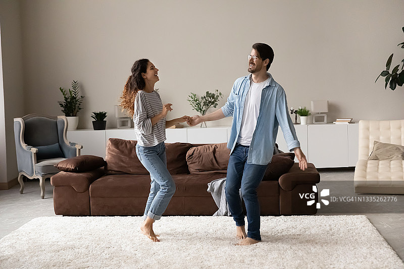 快乐兴奋的千禧夫妇在客厅一起跳舞图片素材