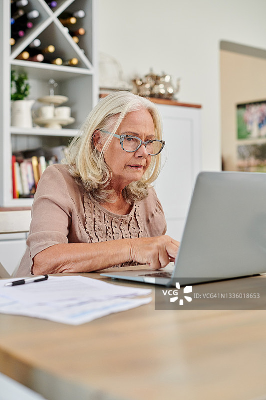 一名高级女性在家里用笔记本电脑处理文书工作图片素材