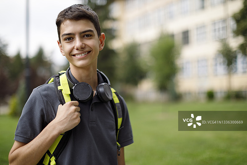 一个微笑的少年在学校前面的肖像图片素材