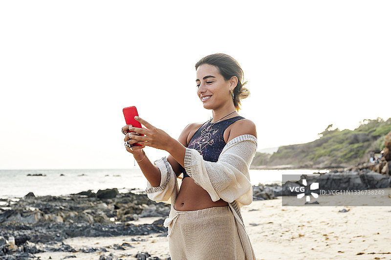 女人站在海滩上用智能手机图片素材