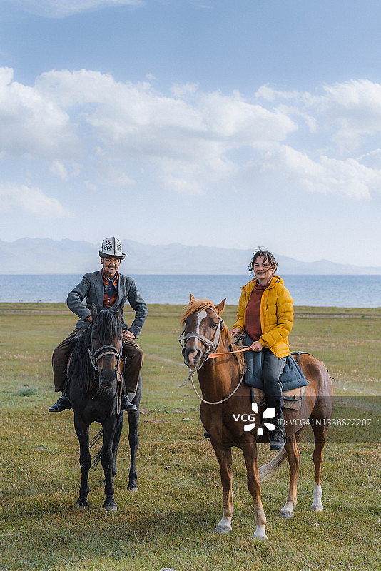 在吉尔吉斯斯坦，一名女子在当地向导的陪同下，骑在Son-Kul湖附近图片素材