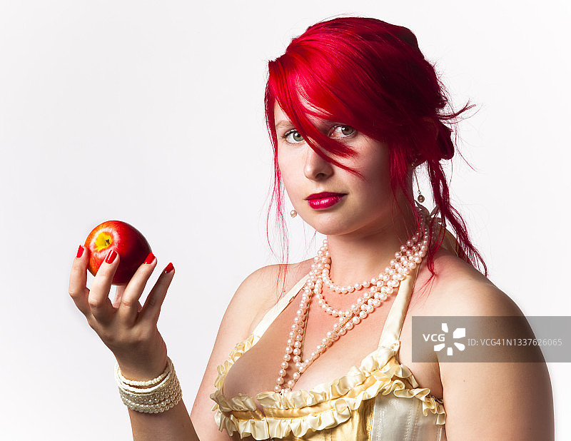 一个长着一头亮红色头发，手里拿着一个红苹果的女人的肖像图片素材