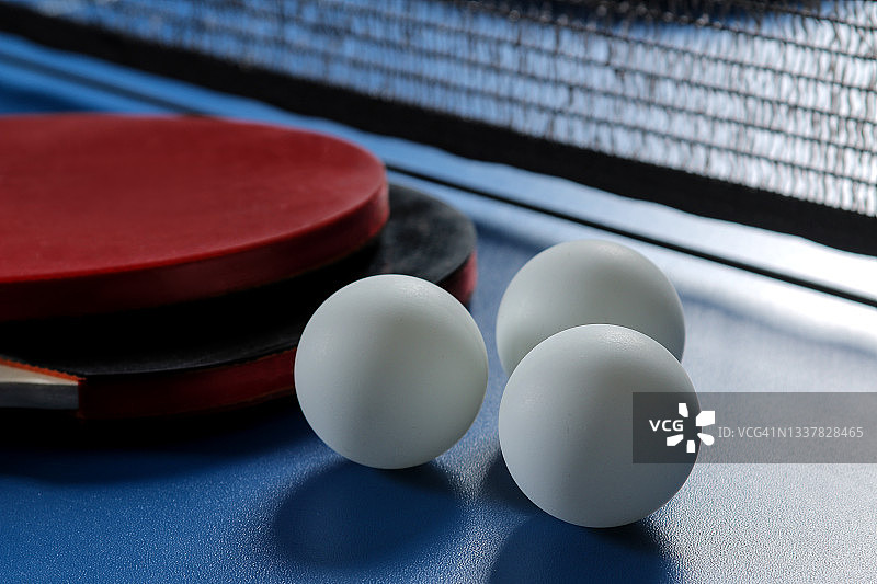 乒乓球。乒乓球拍子和球的配件，放在蓝色的乒乓球桌上。运动。体育游戏。图片素材