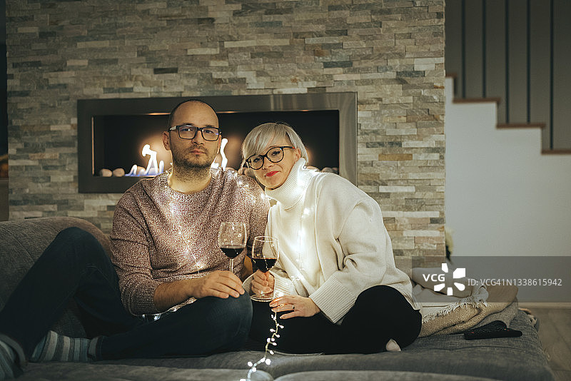 白人夫妇在家里庆祝新年，坐在沙发上喝着一杯酒图片素材