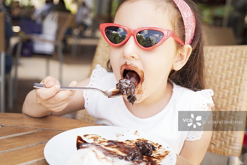 可爱的小女孩在吃巧克力蛋糕图片素材