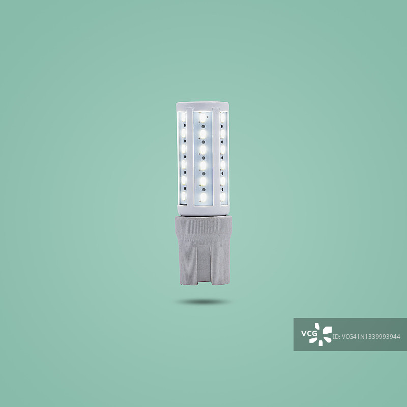 LED节能灯230v在陶瓷插座上隔离绿色粉彩。图片素材