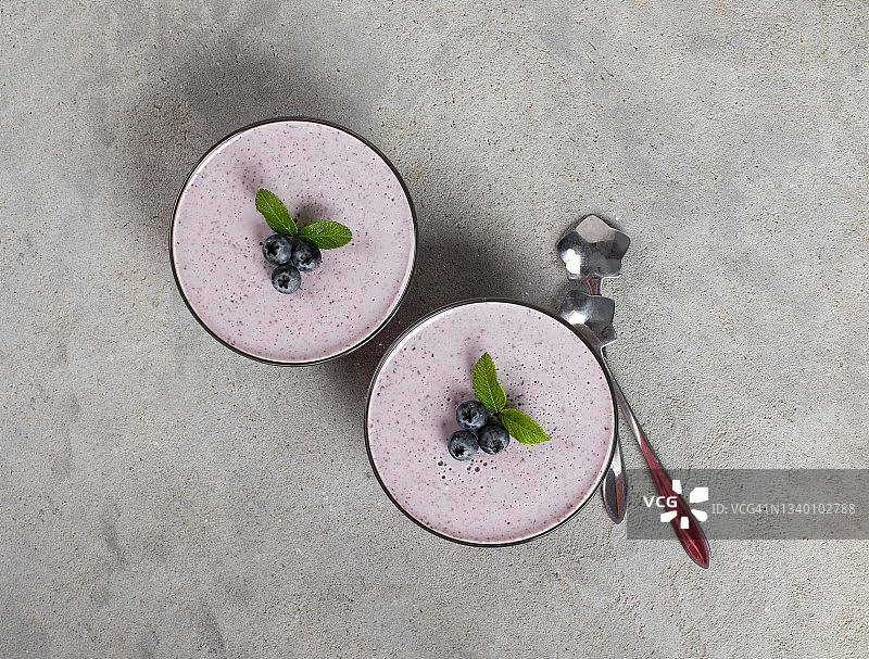 奶油浆果甜点，蓝莓果冻在玻璃上浅灰色背景俯视图图片素材