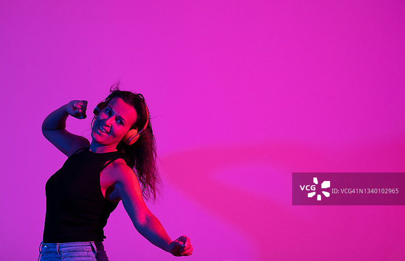 一个年轻女子在紫色背景下听音乐图片素材