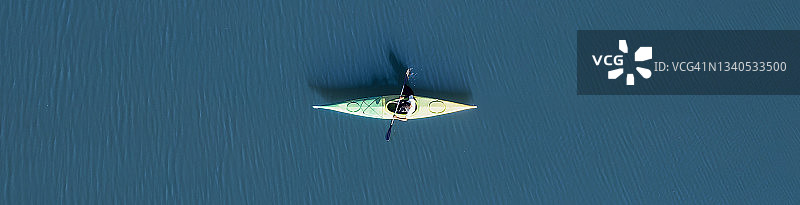 从上面看，鸟瞰图，一个人划着皮划艇在雪松湖上，周围是位于Gennargentu地块东北的supramont山脉。意大利撒丁岛。图片素材