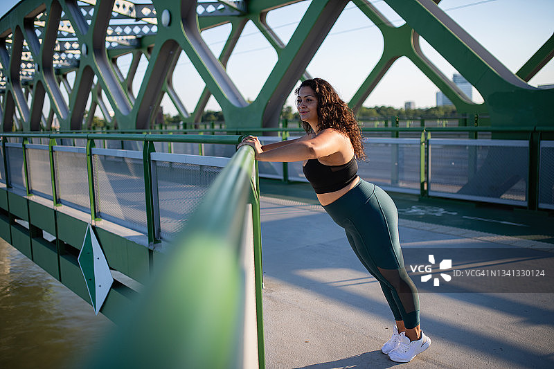 美丽的年轻超重女人的肖像在户外桥在城市，做运动。图片素材