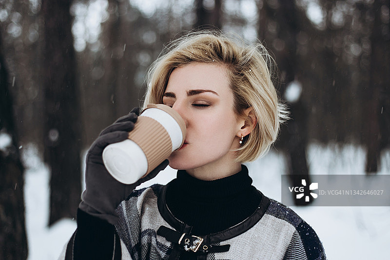年轻女子在森林里喝咖啡。图片素材