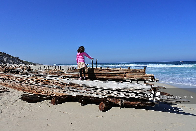 一个澳大利亚女孩站在澳大利亚西部珀斯附近的一艘旧木船残骸上图片素材