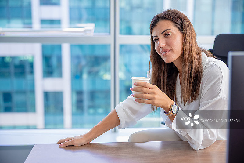 劳累过度的女商人在她的办公桌上用一次性杯子喝咖啡图片素材