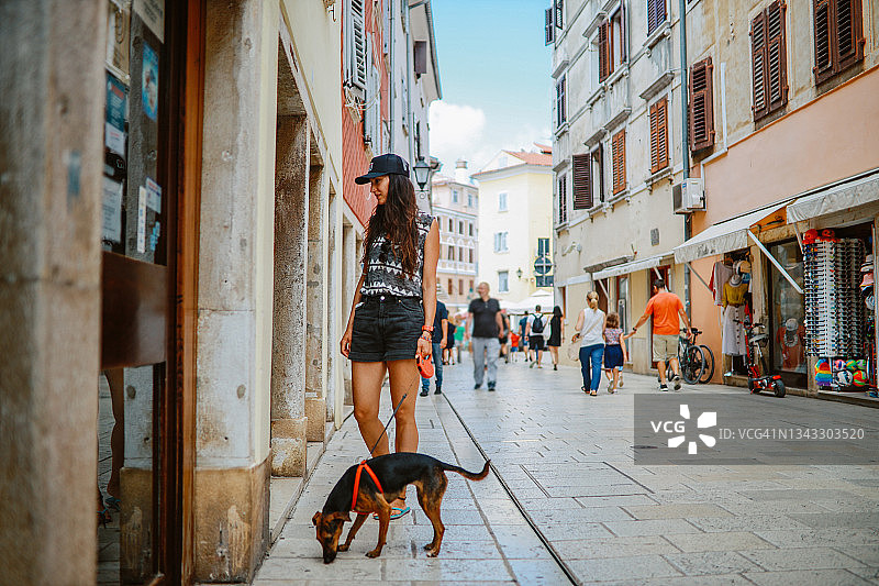 一名女游客在罗维尼古城步行街上遛狗图片素材