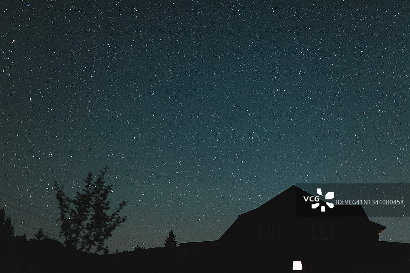 房子和树木的剪影在布满星星的蓝色夜空前图片素材
