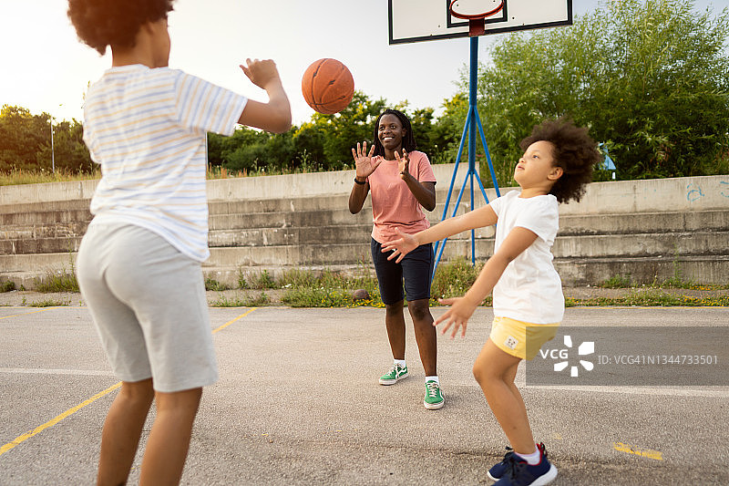 一个活跃健康的黑人家庭，母亲和她的女儿们在户外打篮球图片素材