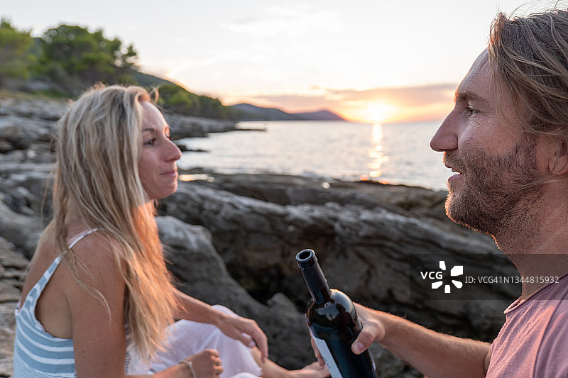 年轻夫妇在日落时在海边喝酒图片素材