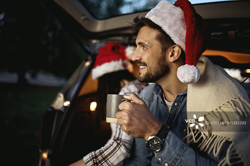 圣诞节，一对相爱的年轻夫妇坐在敞开的汽车后备箱里图片素材