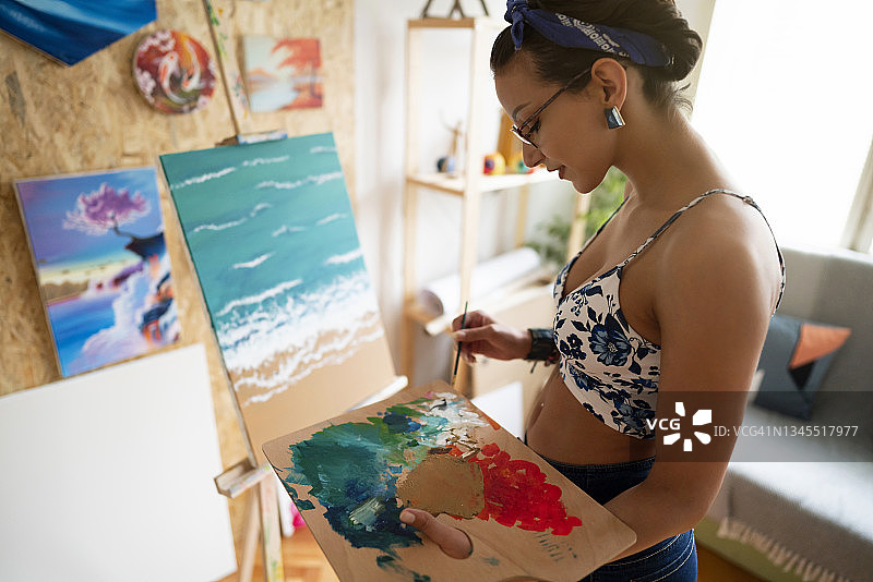 女人，一个艺术家在制作欲望油画的颜色，同时在木艺术家的调色板上混合颜料图片素材