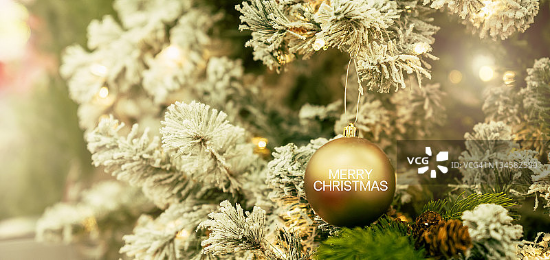 圣诞树用金色和绿色装饰在木地板上。背景中的散焦光线。图片素材