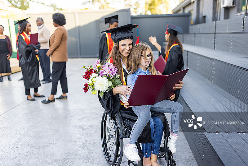 毕业典礼后，年轻的女学生和她的女儿坐在轮椅上图片素材