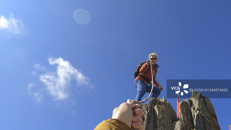 一名女子确保登山运动员上山的POV图片素材
