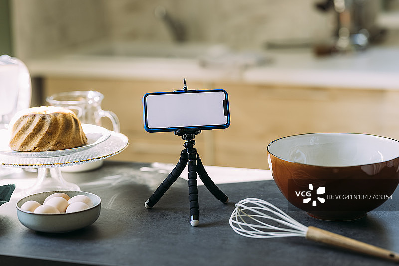 糕点厨师的视频博客:厨房台面上三脚架上的智能手机图片素材