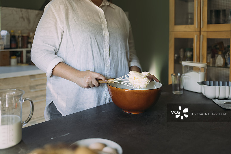 匿名大号女面包师在家庭厨房用搅拌器搅拌面团图片素材