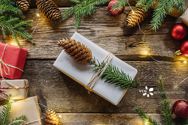圣诞节或新年作文与礼品盒，冷杉树枝，红色球，闪光灯，剪刀和装饰在木头背景。平铺，俯视图。圣诞快乐卡图片素材