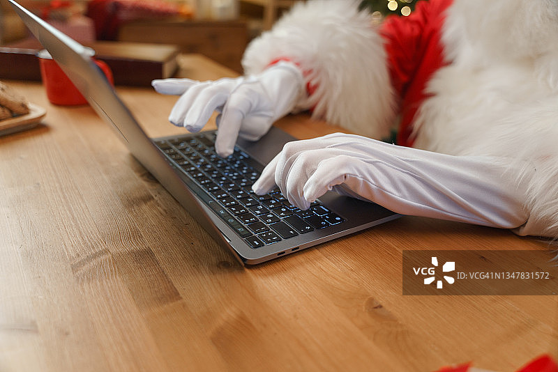 圣诞老人戴着白手套在他的笔记本电脑上打字图片素材