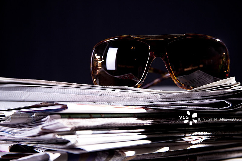 一堆报纸，上面戴着太阳镜。图片素材