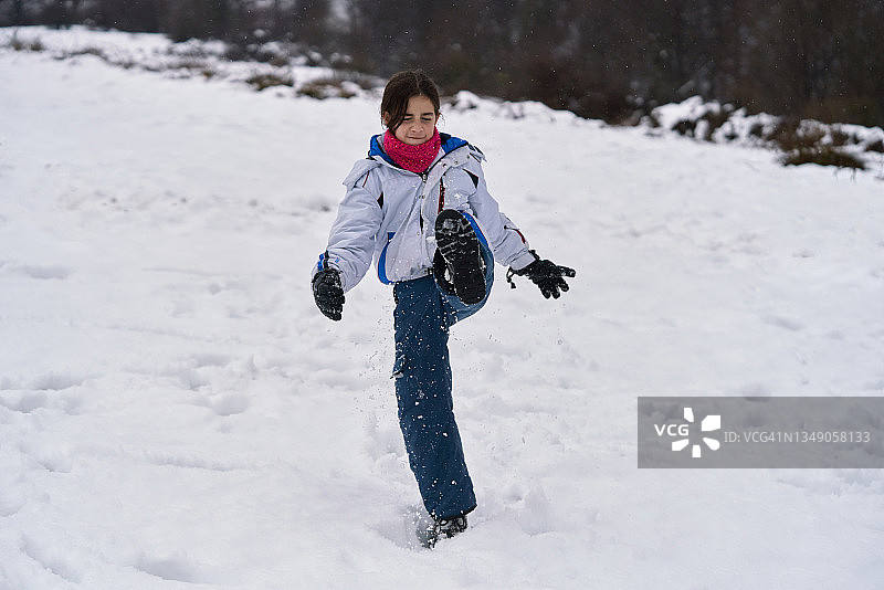 女孩穿着冬衣在山上的雪地上跳来跳去图片素材