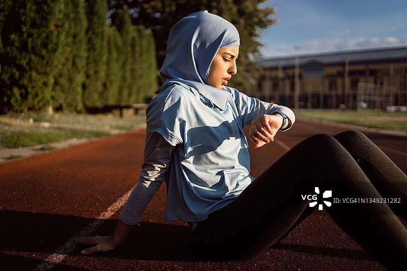 女运动员穿着朴素的运动服，用健身追踪器测量脉搏图片素材