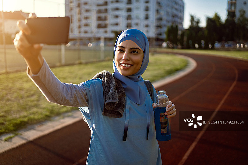 现代穆斯林女运动员用手机自拍图片素材