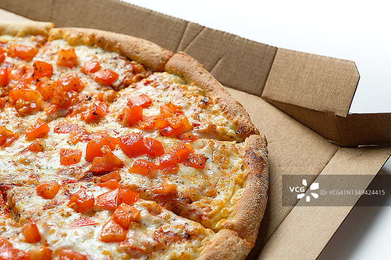 美味的意大利披萨在披萨盒和外卖，在白色背景或桌子上。玛格丽塔比萨配番茄和奶酪，切成块，不含肉。素食的概念，快餐不健康的食品。送货到家或上班。图片素材