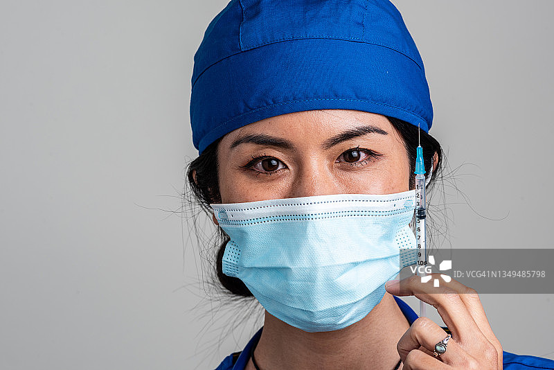 笑容满面的亚洲中年女护士，手里拿着装有疫苗的注射器图片素材