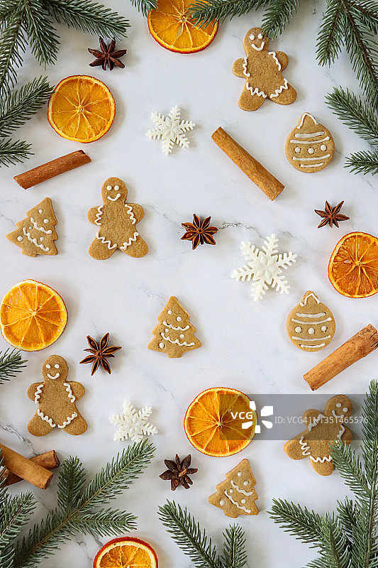 节日的圣诞设计海报的形象，自制的姜饼饼干形状的姜饼人，圣诞树和大理石效果背景上的小饰物，肉桂棒，干桔子片，八角和云杉树枝，圣诞节墙纸图片素材