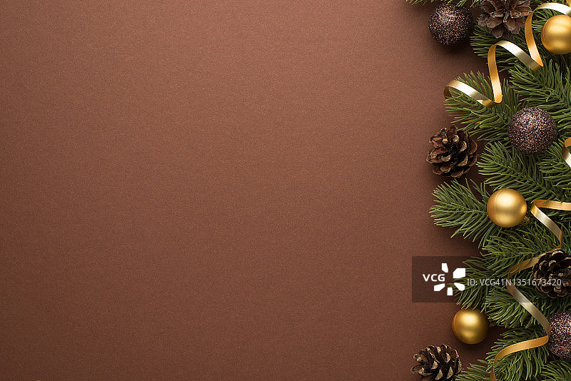 顶部视图照片的金色和棕色的圣诞树球圆锥和松枝上的蛇纹石在孤立的棕色背景与copyspace图片素材