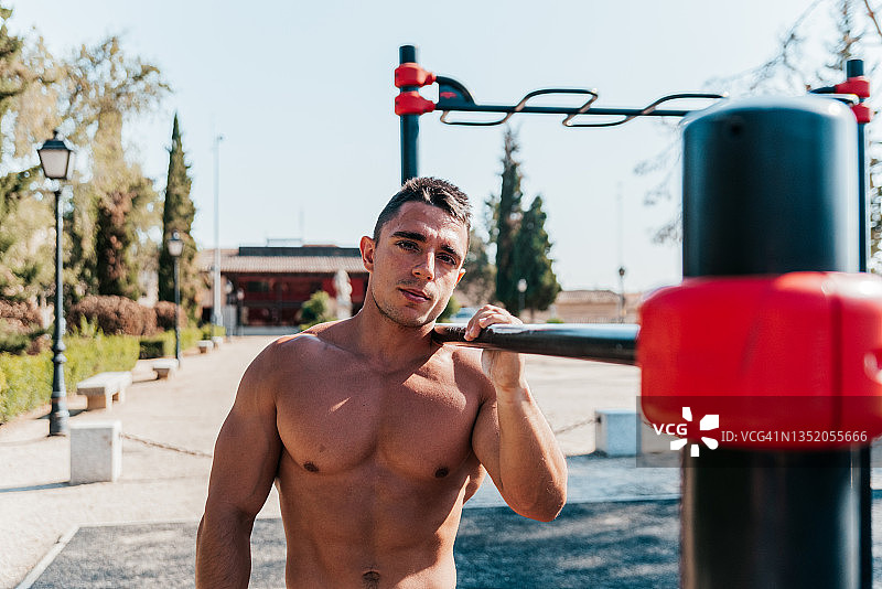 一个肌肉发达的运动员的肖像在一个健美操酒吧公园。图片素材
