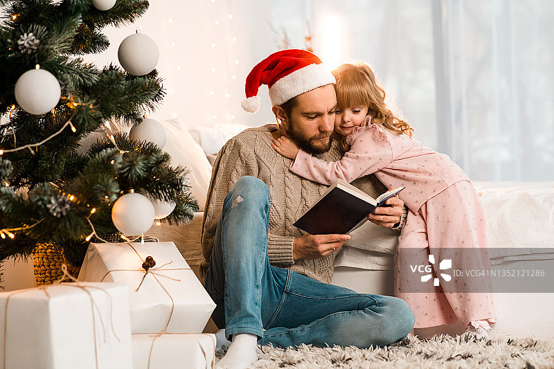 戴圣诞帽的父亲给他心爱的女儿读童话故事图片素材