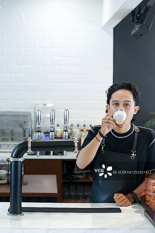 年轻男子咖啡师正在喝一杯咖啡图片素材