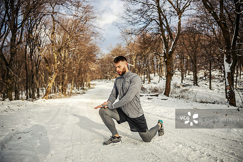 身体健康的运动员在雪天跪在大自然中做热身和伸展运动。冬季健身，健康生活方式图片素材